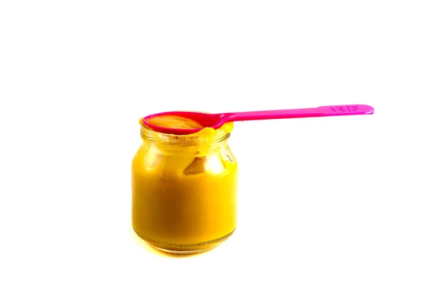 Baby fruit puree in the pot with a plastic spoon — Stock Photo, Image