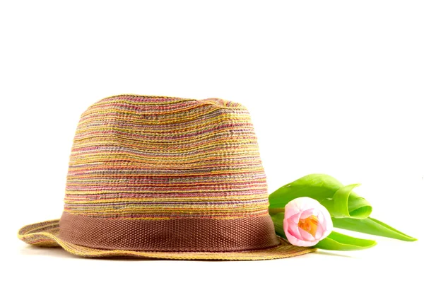 Pink tulip and colored straw hat — Stock Photo, Image