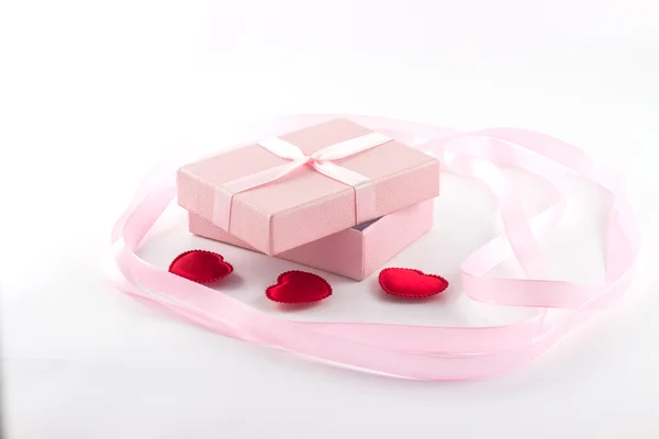Caixa de presente com uma fita rosa e corações vermelhos e uma grande faixa rosa — Fotografia de Stock