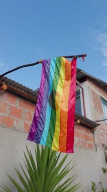Cusco Tahuantinsuyo 'nun yedi renkli bayrağı ahşap bir direğe asılı açık mavi bir gökyüzüne ve tuğla bir binaya. Güneş parlak kumaşı aydınlatır..