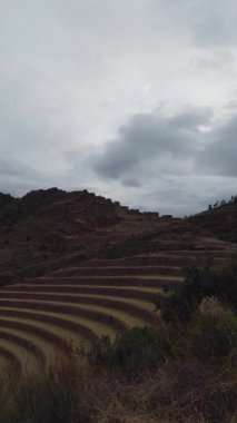 Peru 'nun Kutsal Vadisi' ndeki Pisac arkeolojik sahasındaki eğimli tarım terasları ve taş kalıntıları dramatik bulutlu bir gökyüzüne doğru ilerliyor..