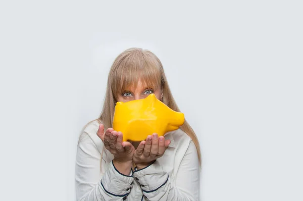 Mulher loira mostra caixa de dinheiro de porco amarelo — Fotografia de Stock