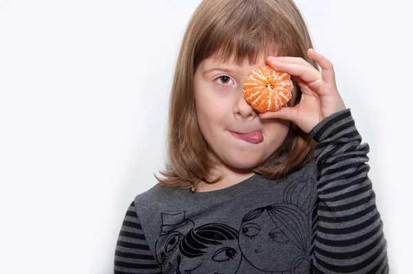 Teen girl with mandarin shows tonque — Stock Photo, Image