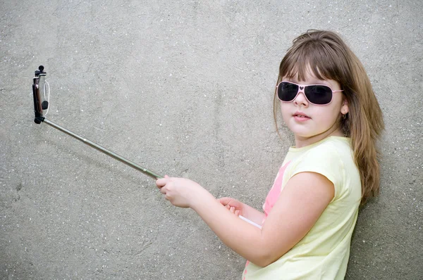 Girl makes selfie with monopod in hands — Stock Photo, Image
