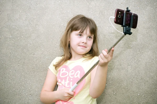 Girl makes selfie with monopod in hands