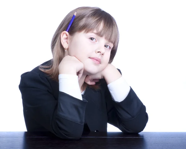 Pěkná školačka v černobílé uniformě sedí u stolu — Stock fotografie