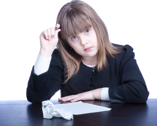 Fin skolflicka i svart-vita uniform sitter vid ett bord — Stockfoto