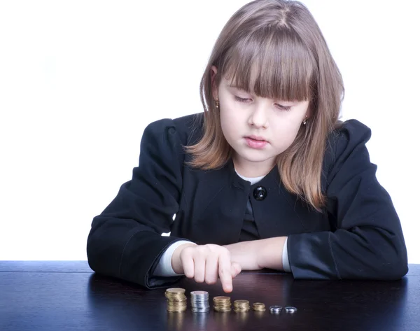 Schönes Mädchen in Schuluniform sitzt an einem Tisch und zählt — Stockfoto