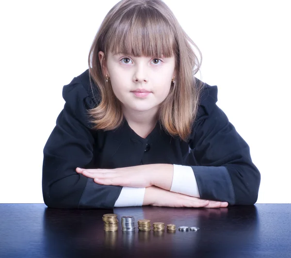 Nettes Mädchen in Schuluniform sitzt an einem Tisch und zählt Münzen — Stockfoto