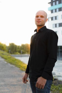 Sokakta siyah gömlekli, sakallı yakışıklı bir adam.