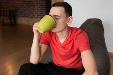 Yakışıklı bir gencin portresi Sabahları bir fincan çayın keyfini çıkarıyor