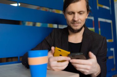 Girişimci kahve molası sırasında iki telefon kullanır.