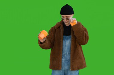 Gözlüklerini çıkaran adam yüzünde ciddi bir ifade olan bir bardağa bakıyor.