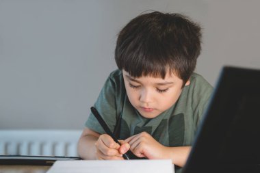 Ödevi için tablet kullanan anaokulu çocuğunun portresi, İnternet, e-öğrenim veya evde eğitim konsepti hakkında dijital tablet arama bilgisini kullanarak ev ödevi yapan çocuğun yumuşak odağı