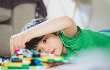 Candid, yerde yatıp plastik oyuncaklarla oynayan mutlu çocuğu, oturma odasında tek başına oynayan pozitif çocuğu, hafta sonları evde dinlenen sevimli çocuğu, çocukların hayal gücünü ve gelişimini çekti.