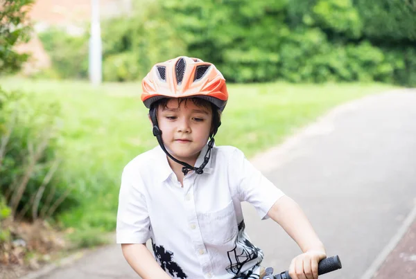Avtive kid wearing a bike helmet, Outdoors portrait Happy kid with smiling face wearing a cycling helmet riding a bicycle in the park, Concept for safety, Healthy childhood