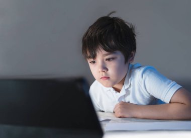 School kid having fun watching cartoon on tablet, Child using digital pad searching the ideas on internet for his homework, Home schooling,  E-learning online education