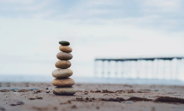 바다로 내려가는 교각으로 찰흙으로 돌무더기 해변에 피라미드 안정감 벌판과 균형을 — 스톡 사진