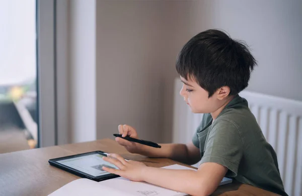 Kid self isolation using tablet for his homework,Child boy using digital tablet searching information on internet during covid 19 lock down,Home schooling,Social Distance,E-learning online education