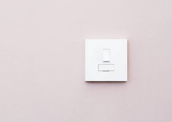 Light switch isolated on light purple wall, A plastic mechanical switch of white color installed on wall for turn on or turn off the lights inside of the room.