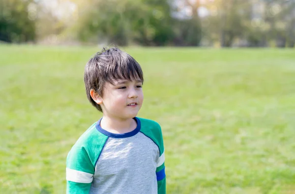 青い草原と木々の背景を持つ公園に立つ幸せな少年の肖像画 笑顔で外を見るアクティブな子供 晴れた日の夏に屋外で遊ぶことを楽しんでいる子供 — ストック写真