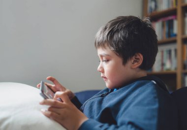 Portre çocuk kanepede uzanmış tablette çizgi film seyrediyor. Dokunmatik kâğıtta oyun oynayan tatlı çocuk. Çalışma odasında kendi kendine eğleniyor ve dinleniyor.