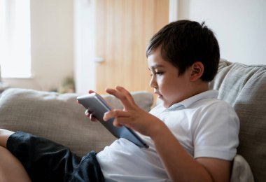 İnternette tablet kullanan okul çocuğu, oyun oynayan çocuk ya da dijital ekranda çizgi film izleyen çocuk, evde dinlenen mutlu çocuk, teknoloji ve sosyal ağ konsepti olan çocuklar.