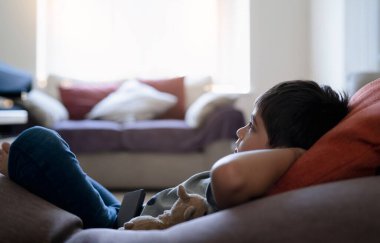 Fasulye çuvalında yatıp TV 'de çizgi film seyreden melez bir çocuk. Güneşli bir yaz gününde, penceresinden parlayan parlak ışıkla çocuk oturma odasında dinleniyor. Çocuk hafta sonu evde dinleniyor. 