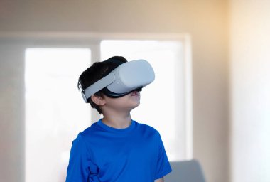 Sanal gerçeklik gözlüğü takan genç bir çocuk. Duygusal Çocuk video oyunları oynuyor ve VR kulaklığı takıyor. Karışık ırkçı çocuğun portresi oturma odasında 3 boyutlu bir aletle geziyor..