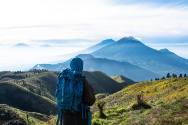 Dişi tırmanışçılar sırt çantalarını taşır ve Prau Dağı 'nın tepesinden dağ manzarasını görürler. : DIENG, Endonezya - 25 Aralık 2017