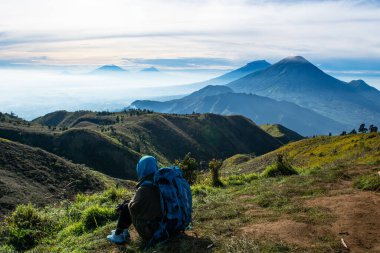 Dişi tırmanışçılar sırt çantalarını taşır ve Prau Dağı 'nın tepesinden dağ manzarasını görürler. : DIENG, Endonezya - 25 Aralık 2017