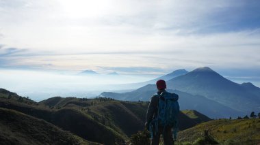 Sırt çantaları taşıyan dağcılar Prau Dağı 'nın tepesinden dağı görüyorlar. : DIENG, Endonezya - 25 Aralık 2017