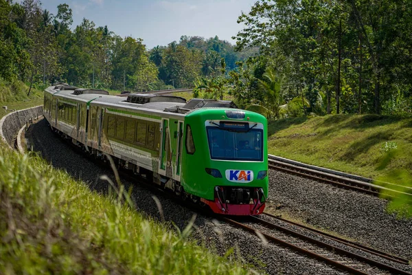 Gündüzleri sık ormanın sol ve sağ görüşüyle çift yönlü bir hat üzerinde giden ticari bir tren. : Kulon Progo, Endonezya - 07 Ağustos 2021