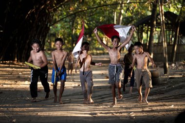 Bayrağı taşıyan Endonezya 'nın bağımsızlık baskısında oynayan ve heyecanlanan köy çocuklarının konsept fotoğrafı. : Bantul, Endonezya - 15 Ağustos 2021