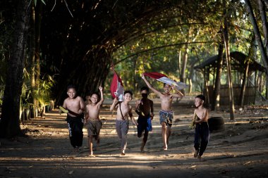 Bayrağı taşıyan Endonezya 'nın bağımsızlık baskısında oynayan ve heyecanlanan köy çocuklarının konsept fotoğrafı. : Bantul, Endonezya - 15 Ağustos 2021