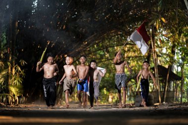 Bayrağı taşıyan Endonezya 'nın bağımsızlık baskısında oynayan ve heyecanlanan köy çocuklarının konsept fotoğrafı. : Bantul, Endonezya - 15 Ağustos 2021
