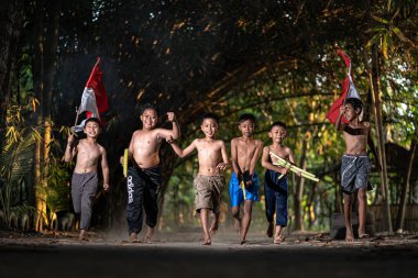 Bayrağı taşıyan Endonezya 'nın bağımsızlık baskısında oynayan ve heyecanlanan köy çocuklarının konsept fotoğrafı. : Bantul, Endonezya - 15 Ağustos 2021