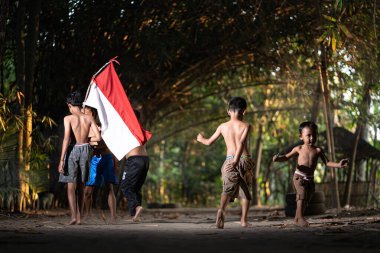 Bayrağı taşıyan Endonezya 'nın bağımsızlık baskısında oynayan ve heyecanlanan köy çocuklarının konsept fotoğrafı. : Bantul, Endonezya - 15 Ağustos 2021