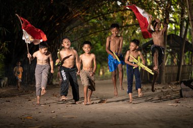 Bayrağı taşıyan Endonezya 'nın bağımsızlık baskısında oynayan ve heyecanlanan köy çocuklarının konsept fotoğrafı. : Bantul, Endonezya - 15 Ağustos 2021