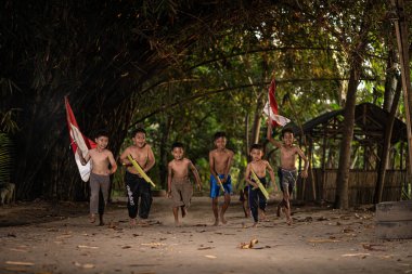 Bayrağı taşıyan Endonezya 'nın bağımsızlık baskısında oynayan ve heyecanlanan köy çocuklarının konsept fotoğrafı. : Bantul, Endonezya - 15 Ağustos 2021
