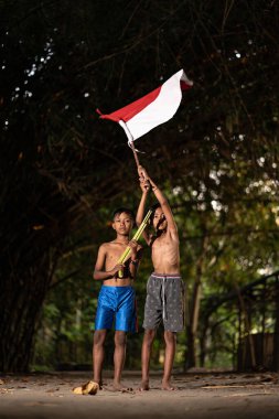 Bayrağı taşıyan Endonezya 'nın bağımsızlık baskısında oynayan ve heyecanlanan köy çocuklarının konsept fotoğrafı. : Bantul, Endonezya - 15 Ağustos 2021