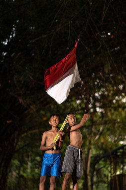Bayrağı taşıyan Endonezya 'nın bağımsızlık baskısında oynayan ve heyecanlanan köy çocuklarının konsept fotoğrafı. : Bantul, Endonezya - 15 Ağustos 2021