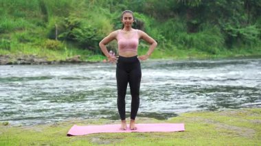 Bacak sallama kası yapan kız nehir altyapısı ile doğada esneme hareketleri yapıyor. Yüksek kalite 4k görüntü