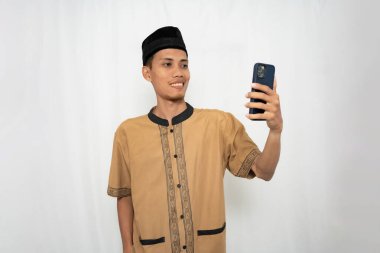 Geleneksel giysiler içinde elinde akıllı telefon tutan genç bir adam.