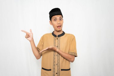 Geleneksel bir kıyafet ve şapkayla el kol hareketi yapan genç bir adam.