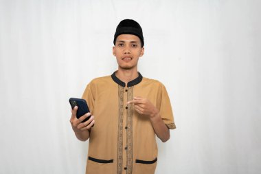 Geleneksel giysiler giymiş genç bir adam elinde akıllı bir telefon ve el kol ile