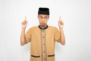 Geleneksel giysiler giymiş genç bir adam iki eliyle yukarıya bakıyor.