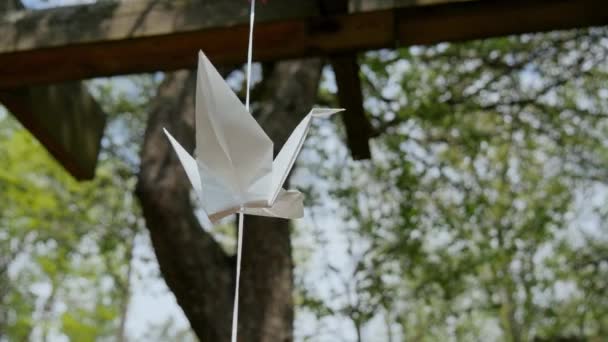 Білий паперовий журавель на струнних хвилях під вітром. Японські оріґамі в парку. — стокове відео