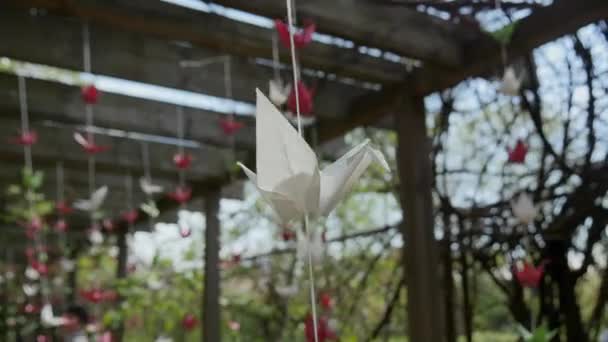 Grue en papier blanc sur corde balancée dans le vent. Chiffre origami japonais dans le parc — Video