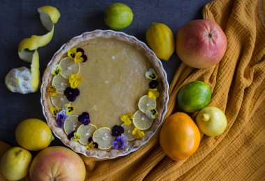 Yabani nonoş çiçekleriyle süslenmiş limonlu turta. Güzel tatlı manzaralı fotoğraf. Kopyalama alanı olan gri arkaplan. 